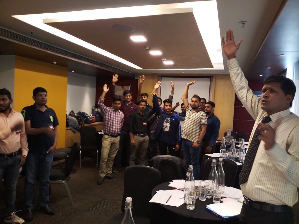 Participants raising hands during an interactive leadership workshop facilitated by Mind Makers Training